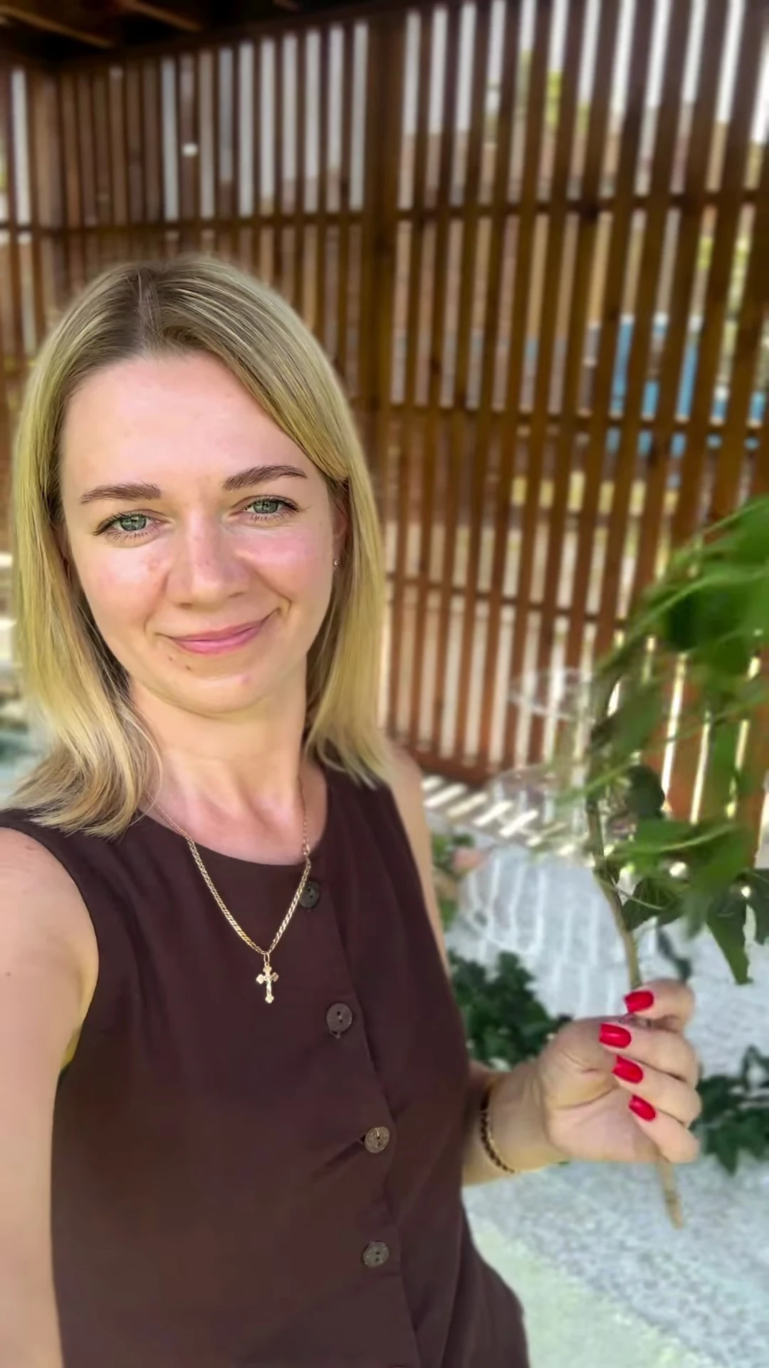 Марина Оленко усміхається, тримаючи зелень у флористичній майстерні